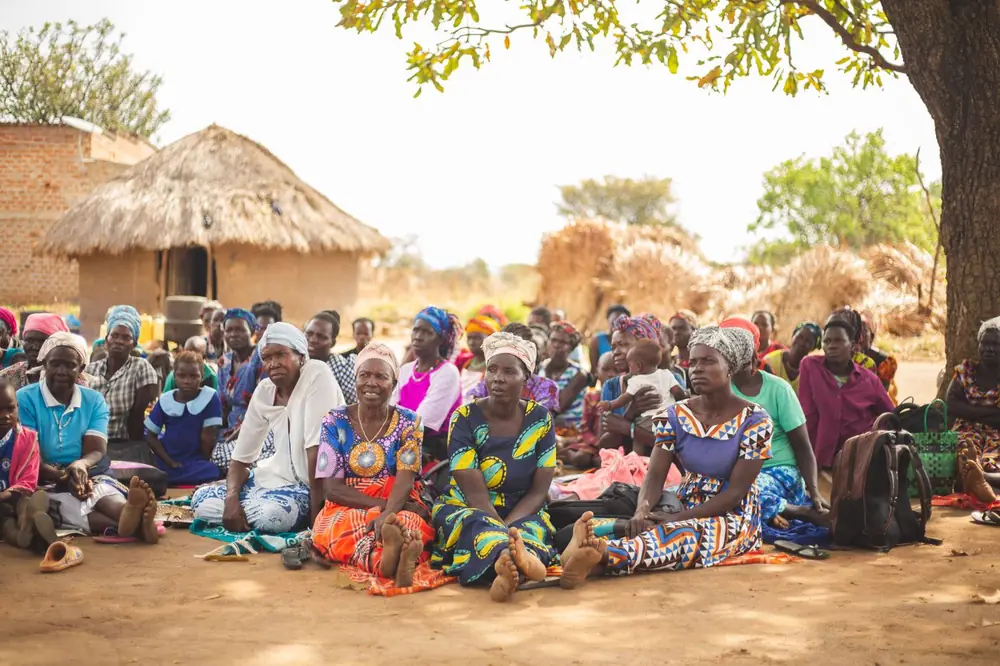 A village gathering with people seated together in colourful dress