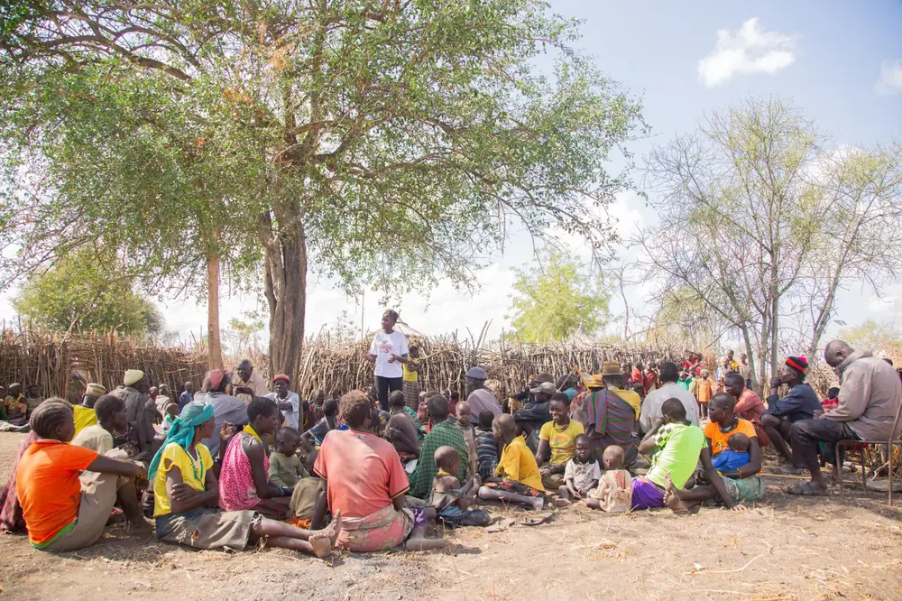 Adults and children meeting together under a tree