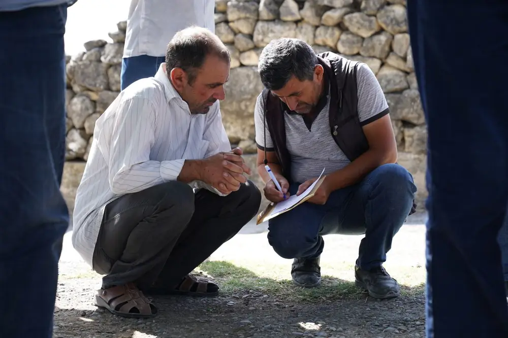 Two people reviewing plans on a clipboard in a field